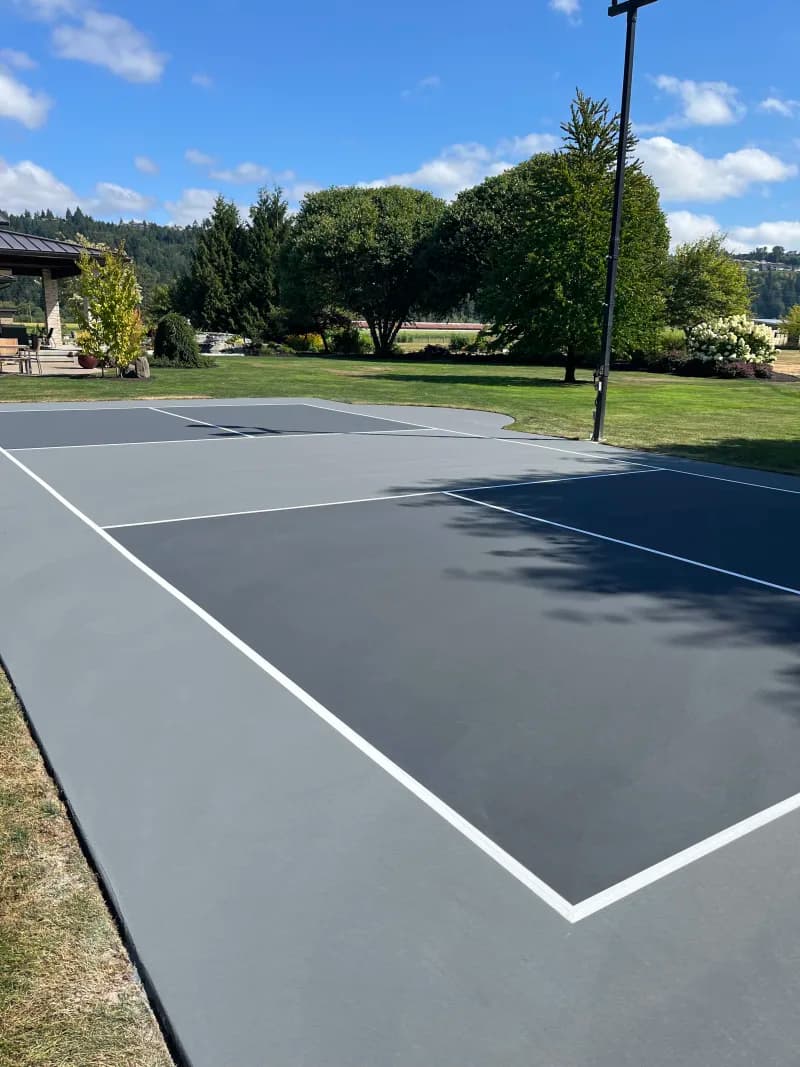 Finished slate and gray backyard pickleball court with white lines in Sumner, Washington